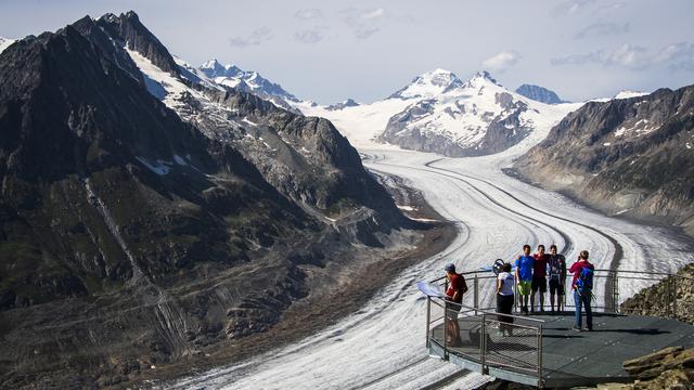 Des personnes observent le glacier d'Aletsch depuis le point de vue de l'Eggishorn, le dimanche 15 août 2021 au-dessus de Fiesch. Le glacier d'Aletsch est le plus grand glacier des Alpes, situe dans le sud de la Suisse dans le canton du Valais. [Keystone - Jean-Christophe Bott]