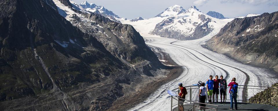 Des personnes observent le glacier d'Aletsch depuis le point de vue de l'Eggishorn, le dimanche 15 août 2021 au-dessus de Fiesch. Le glacier d'Aletsch est le plus grand glacier des Alpes, situe dans le sud de la Suisse dans le canton du Valais. [Keystone - Jean-Christophe Bott]