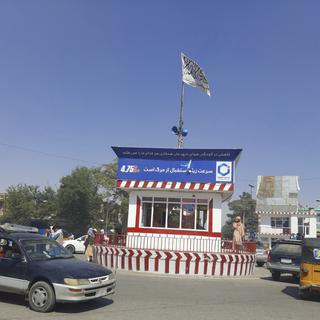 Un drapeau taliban flotte sur la rue principale de Kunduz, le 8 août 2021. [Keystone - Abdullah Sahil]
