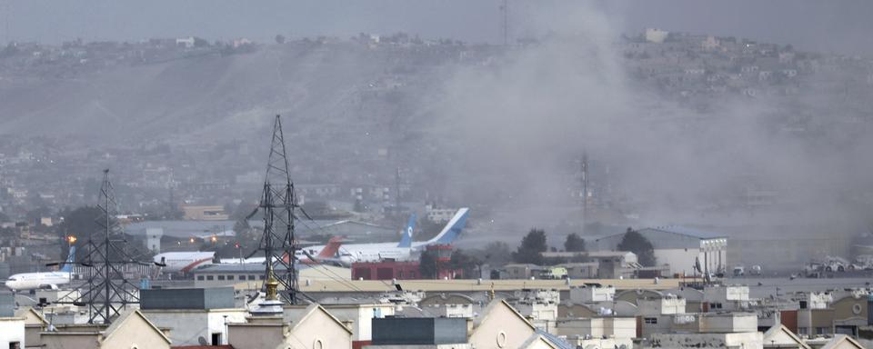 De la fumée est visible depuis l'extérieur de l'aéroport de Kaboul, où une explosion a eu lieu et aurait fait plusieurs victimes. [Keystone - Wali Sabawoon]