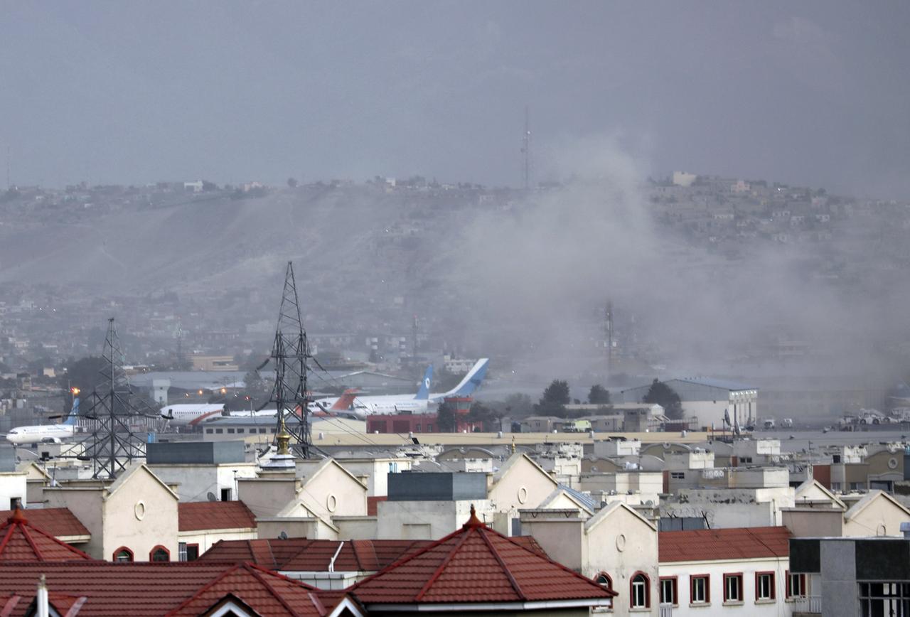 De la fumée est visible depuis l'extérieur de l'aéroport de Kaboul, où une explosion a eu lieu et aurait fait plusieurs victimes. [Keystone - Wali Sabawoon]