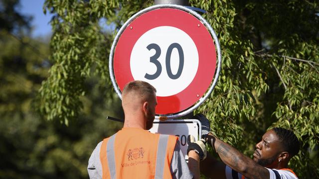 Installation d'un panneau interdisant de rouler à plus de 30km/h, en septembre 2021, à Lausanne. [Keystone - Laurent Gillieron]