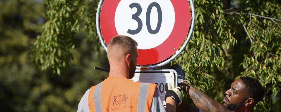 Installation d'un panneau interdisant de rouler à plus de 30km/h, en septembre 2021, à Lausanne. [Keystone - Laurent Gillieron]