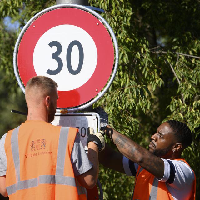 Installation d'un panneau interdisant de rouler à plus de 30km/h, en septembre 2021, à Lausanne. [Keystone - Laurent Gillieron]
