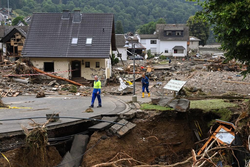 Deux hommes marchent au milieu de maisons détruites après les dégâts importants causés par les inondations à Schuld près de Bad Neuenahr-Ahrweiler, dans l'ouest de l'Allemagne, le 16 juillet 2021. [AFP - Christof Stache]
