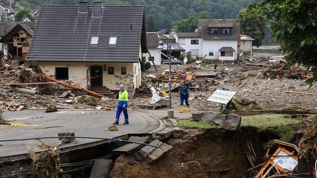 Deux hommes marchent au milieu de maisons détruites après les dégâts importants causés par les inondations à Schuld près de Bad Neuenahr-Ahrweiler, dans l'ouest de l'Allemagne, le 16 juillet 2021. [AFP - Christof Stache]