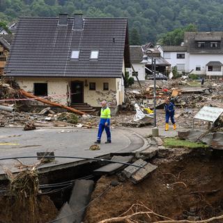 Deux hommes marchent au milieu de maisons détruites après les dégâts importants causés par les inondations à Schuld près de Bad Neuenahr-Ahrweiler, dans l'ouest de l'Allemagne, le 16 juillet 2021. [AFP - Christof Stache]