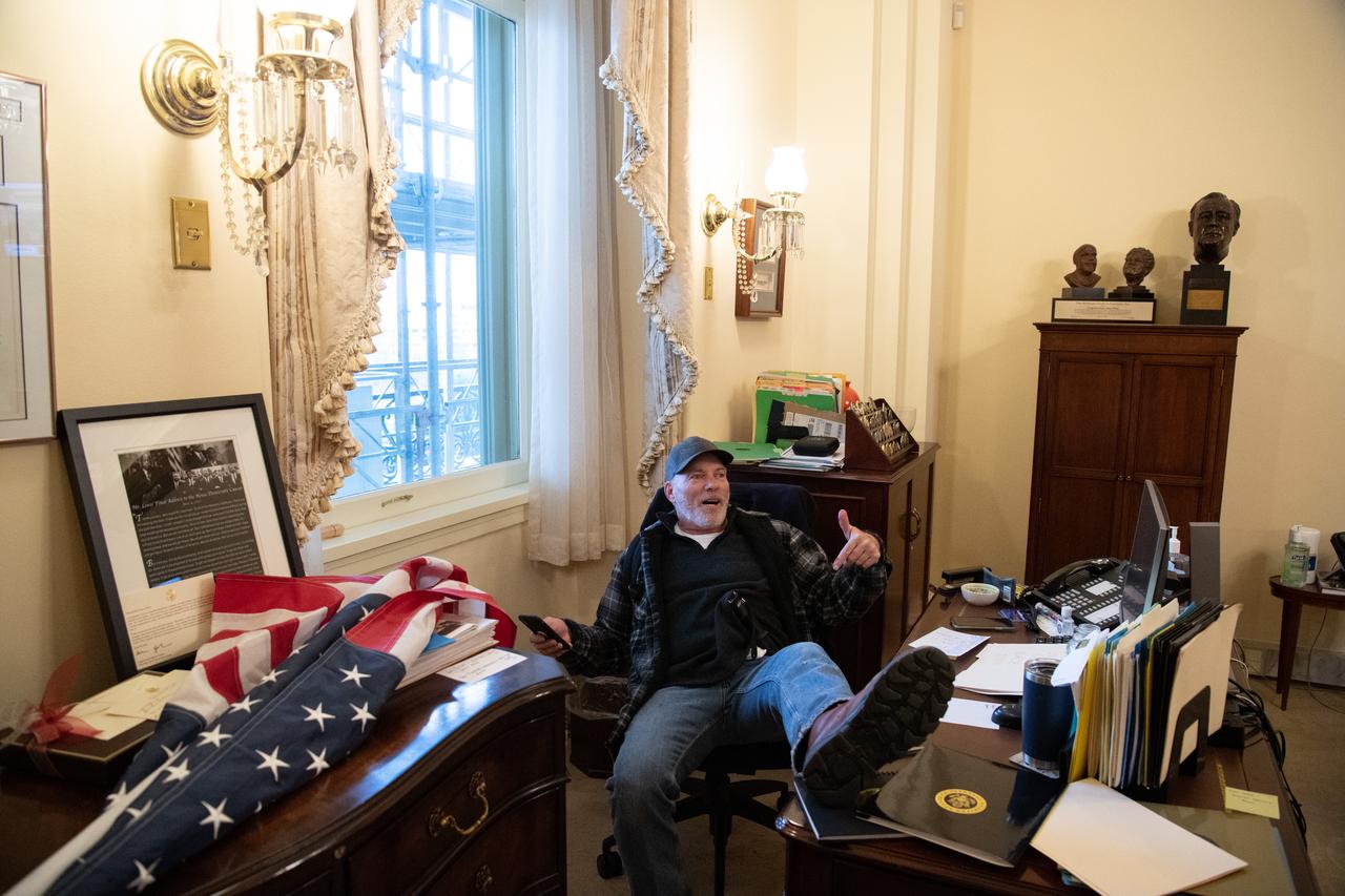 Richard Barnett, un partisan de Donald Trump, est assis au bureau de Nancy Pelosi, la présidente de la Chambre américaine des représentants. [AFP - SAUL LOEB]