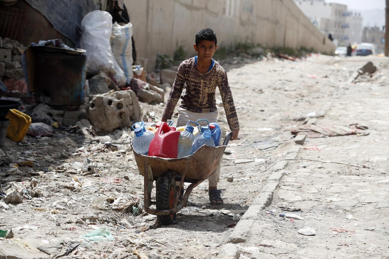 Un jeune garçon ramène de l'eau dans des bouteilles qu'il a remplies auprès d'une association charitable, à Sanaa. Yémen, le 18 juin 2020. [Keystone/epa - Yahya Arhab]