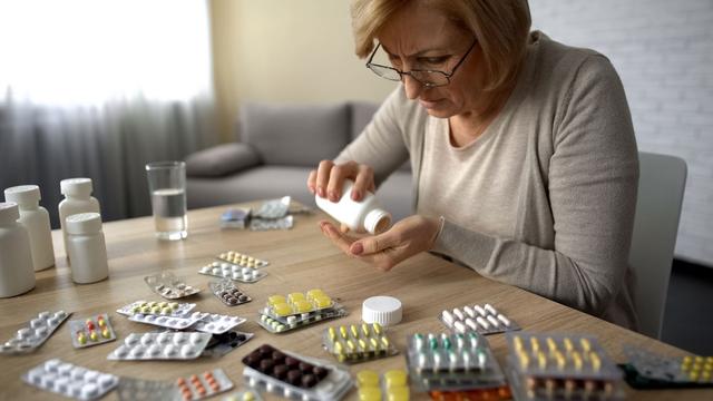 Une femme compte ses médicaments. [Depositphotos - motortion]