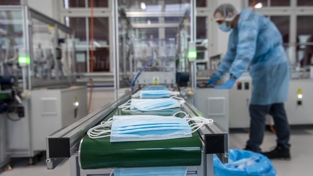 Un ouvrier contrôle la production de masques d'hygiène sur une machine de la nouvelle fabrique de masques chirurgicaux Amyna 3 lors de la crise du Coronavirus (Covid-19), le vendredi 20 novembre 2020 à Corgémont dans le Jura bernois. [KEYSTONE - JEAN-CHRISTOPHE BOTT]