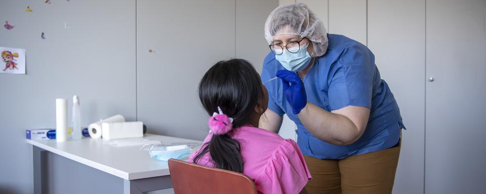 Une enfant se soumettant à un dépistage du Covid-19. [Keystone - Jean-Christophe Bott]