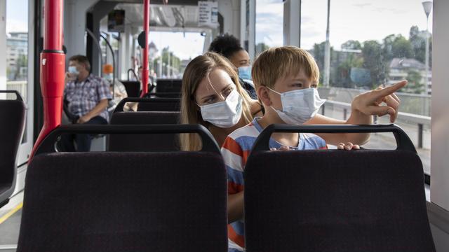 Une femme et un enfants masqués dans le tram à Berne, le 6 juillet 2020. [Keystone - Peter Klaunzer]