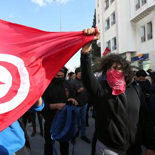 Un manifestant tient un drapeau tunisien le 26 janvier 2021. [Keystone/EPA - Mohamed Messara]
