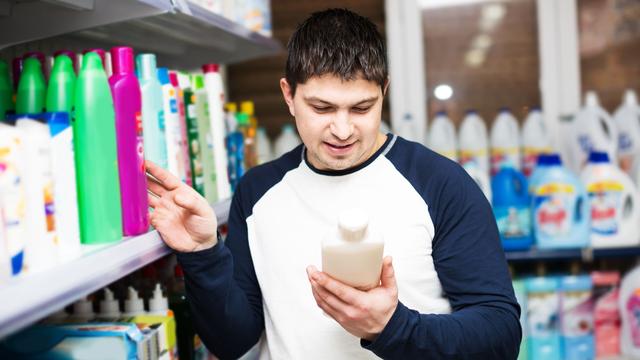 Un homme regarde l'étiquette d'un produit dans un supermarché. [Depositphotos - Jim_Filim]