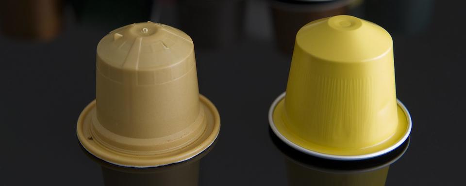 Une capsule de café biodégradable Ethical Coffee Company (à gauche) à côté d'une capsule de café Nespresso (à droite). [Keystone - Jean-Christophe Bott]