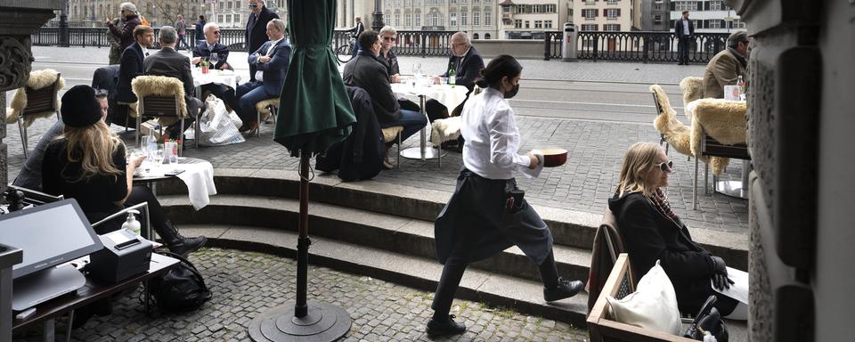 Des clients profitent de la réouverture des terrasses de restaurant sur les bords de la Limmat à Zurich le 19 avril 2021. [Keystone - Gaetan Bally]