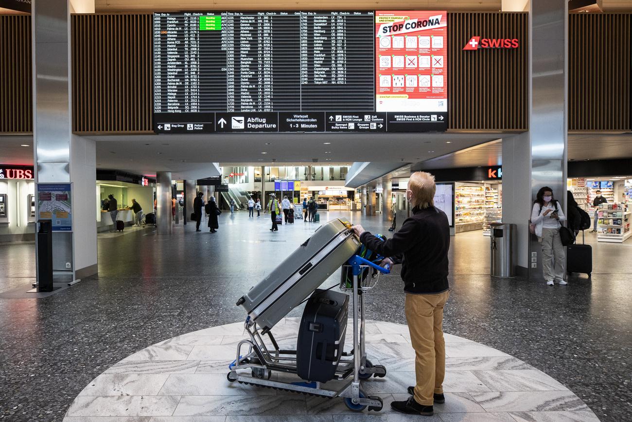 Un homme regarde le tableau des départ dans l'aéroport de Zurich le 1er avril 2021. [Keystone - Alexandra Wey]