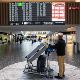 Un homme regarde le tableau des départ dans l'aéroport de Zurich le 1er avril 2021. [Keystone - Alexandra Wey]
