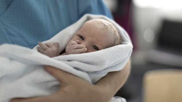 Un bébé dans les bras de son père. [Keystone - Gaëtan Bally]