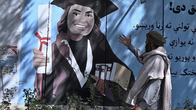 Jeudi 9 septembre: à Kaboul, un homme gesticule face à une peinture murale montrant une jeune femme diplômée. [AFP - Wakil Kohsar]