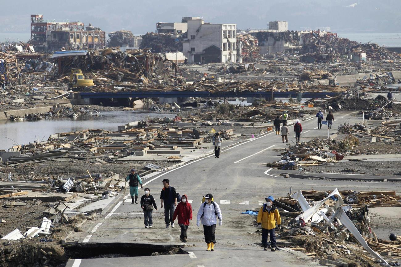 Trois jours après le tremblement de terre et le tsunami, des gens marchent dans les décombres de Minamisanriku. Japon, le 14 mars 2011. [Keystone/ap photo - Tsuyoshi Matsumoto/The Yomiuri Shimbun]