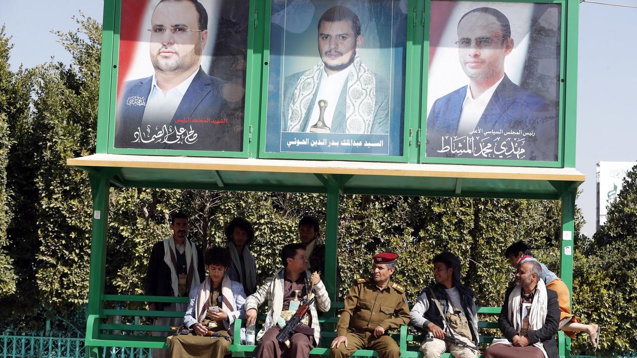 Des miliciens houthis armé et des partisans sont assis sous les portraits de trois leaders du mouvement, dont Abdul-Malik al-Houthi (au milieu). Sanaa, Yémen, le 11 janvier 2021. [Keystone/epa - Yahya Arhab]