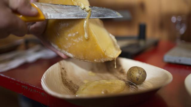 Un demi-pain de fromage à raclette fondu et accompagné de pommes de terre. [Keystone - Gaetan Bally]