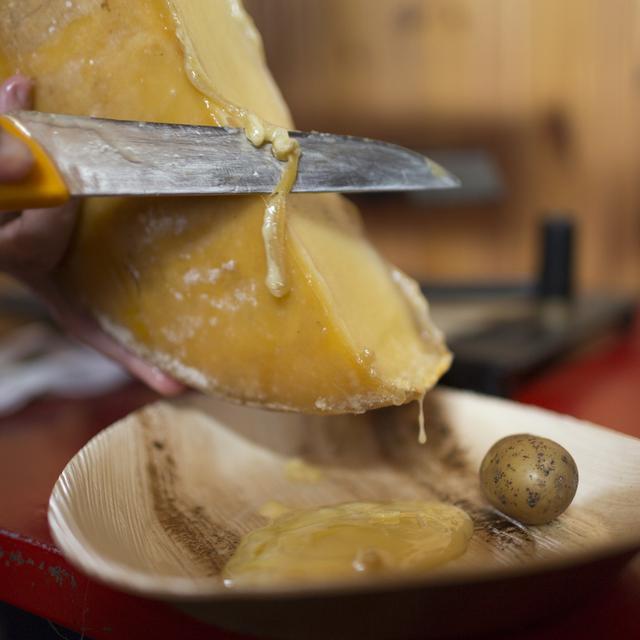 Un demi-pain de fromage à raclette fondu et accompagné de pommes de terre. [Keystone - Gaetan Bally]