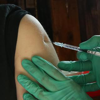 Une jeune femme reçoit un vaccin contre le coronavirus. [Keystone/DPA - Wolfgang Kumm]