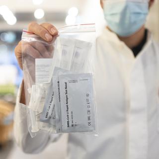 Un pharmacien tient un sachet contenant des autotests pour le coronavirus en avril 2021. [Keystone - Ennio Leanza]