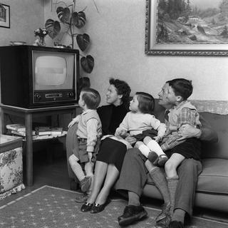 Image d'archive: la famille Schuetz de Spiegel, près de Berne, est assise devant la télévision dans son salon, le 20 mars 1957. [KEYSTONE - PHOTOPRESS-ARCHIVE/KRAFT]
