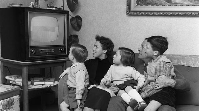 Image d'archive: la famille Schuetz de Spiegel, près de Berne, est assise devant la télévision dans son salon, le 20 mars 1957. [KEYSTONE - PHOTOPRESS-ARCHIVE/KRAFT]