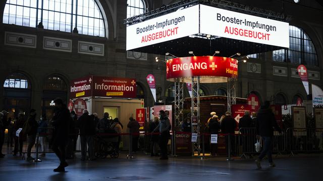 Un panneau d'affichage numérique indique "vaccin de rappel complet" alors que des personnes font la queue au village de vaccination dans le grand hall de la gare centrale de Zurich, mardi 9 novembre 2021 à Zurich. [Keystone - Michael Buholzer]