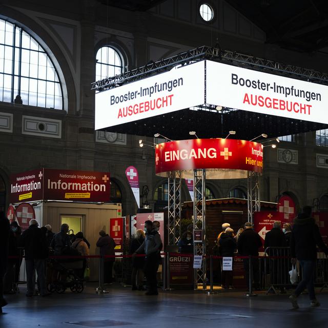 Un panneau d'affichage numérique indique "vaccin de rappel complet" alors que des personnes font la queue au village de vaccination dans le grand hall de la gare centrale de Zurich, mardi 9 novembre 2021 à Zurich. [Keystone - Michael Buholzer]