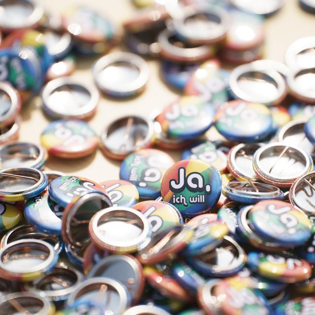 Des pin's avec l'inscription "Oui, je veux" à l'occasion du lancement de la campagne "Oui au mariage pour tous" le dimanche 27 juin 2021. [Keystone - Manuel Lopez]