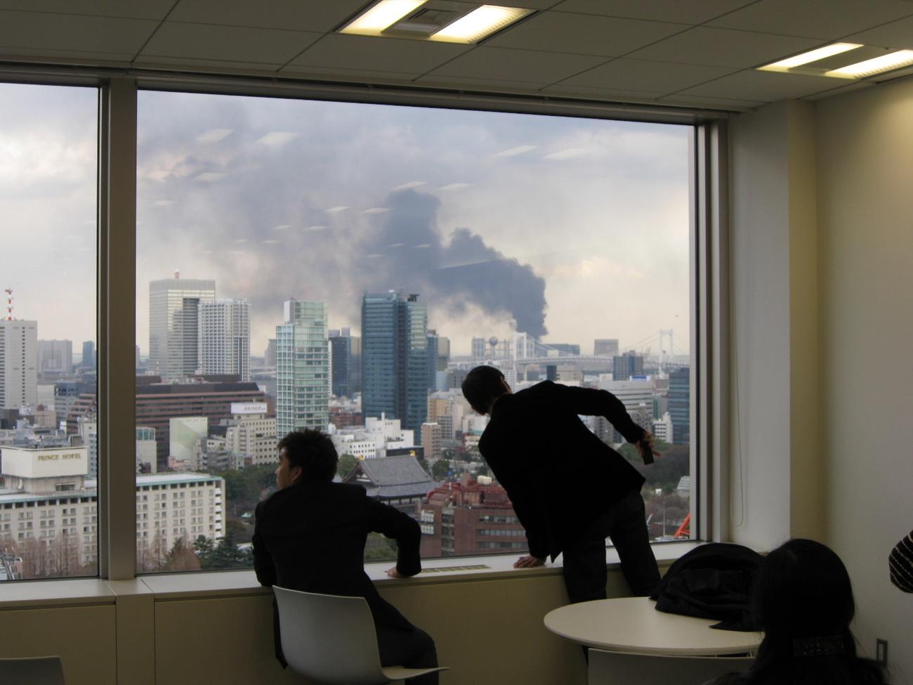 De la fumée s'élève à Tokyo après le tremblement de terre massif de 9,0 sur l'échelle de Richter, au large de la côte de Fukushima. Japon, le 11 mars 2011. [Keystone/ap - Feng Wuyong/Xinhua]