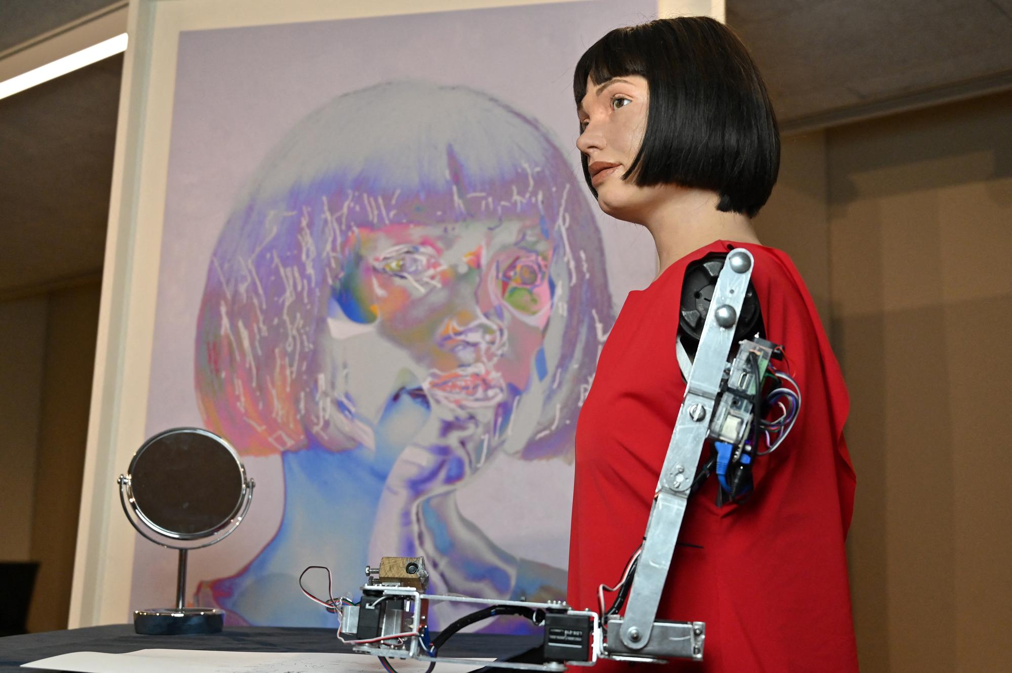 Le robot Ai-Da aux côtés de son autoportrait au Design Museum de Londres, le 14 mai 2021. [AFP - Glyn Kirk]