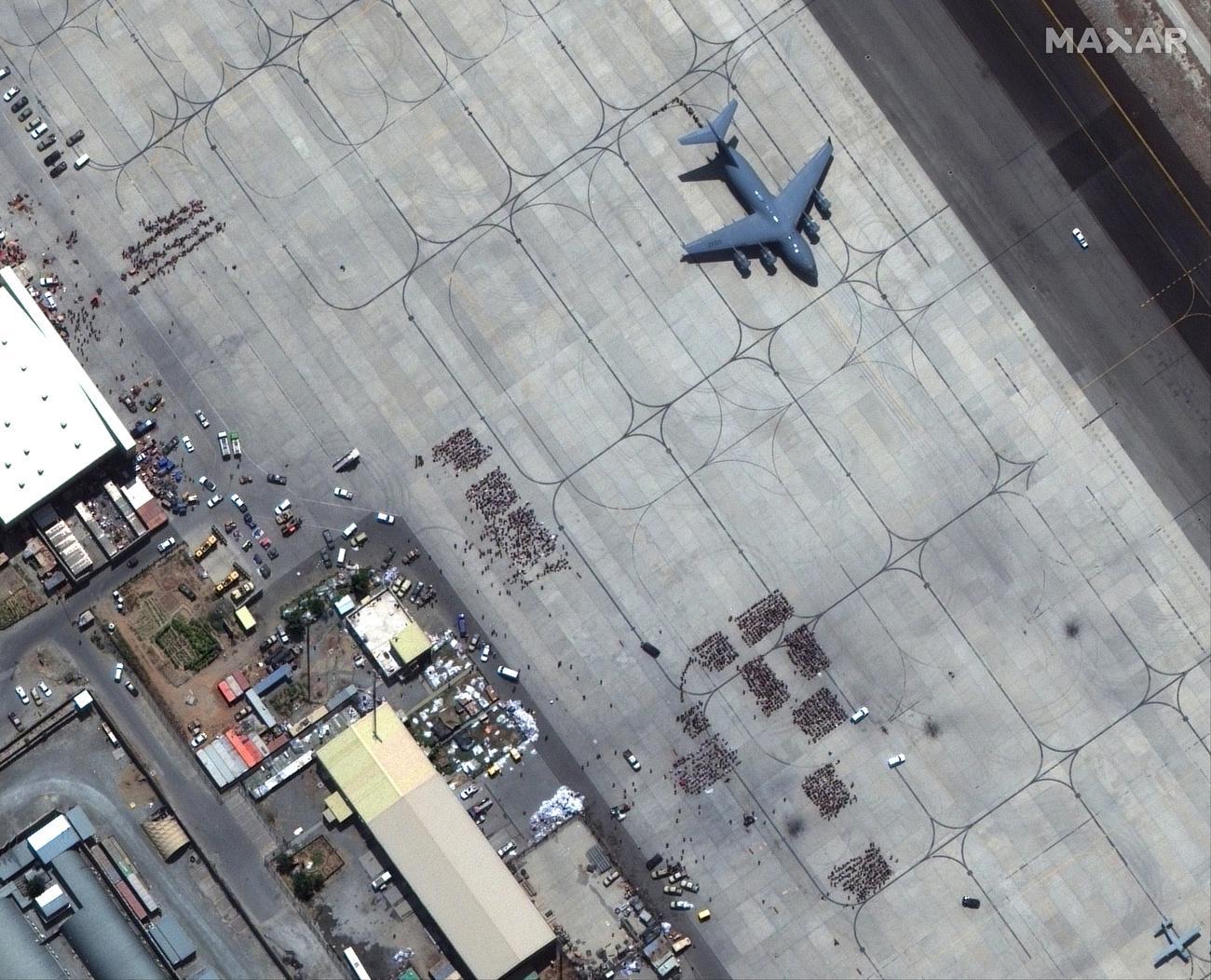 Des personnes attendent d'être évacuées sur le tarmac de l'aéroport de Kaboul, le 23 août 2021. [Keystone - Satellite image ©2021 Maxar Technologies via AP]