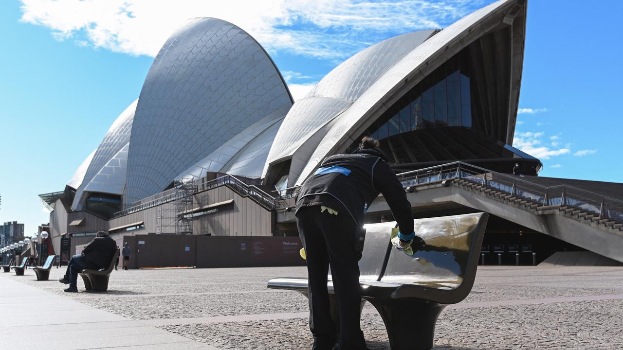 Une personne nettoie un banc public à Sydney le 26 juin 2021, jour du reconfinement total de la ville. [AFP - Saeed Khan]
