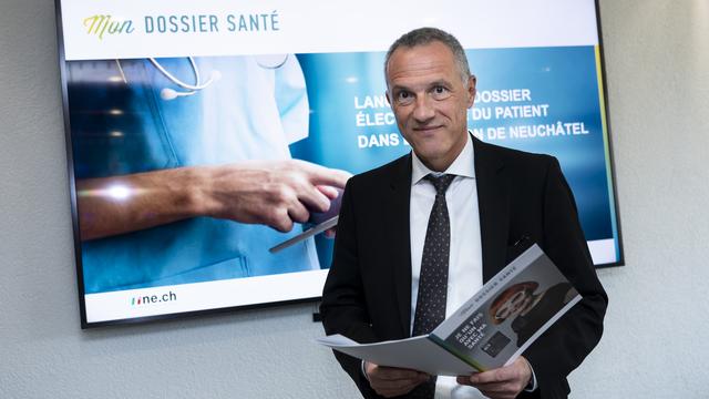 Le conseiller d'Etat neuchatelois Laurent Kurth consulte une brochure sur "Mon Dossier Santé". [Keystone - Jean-Christophe Bott]