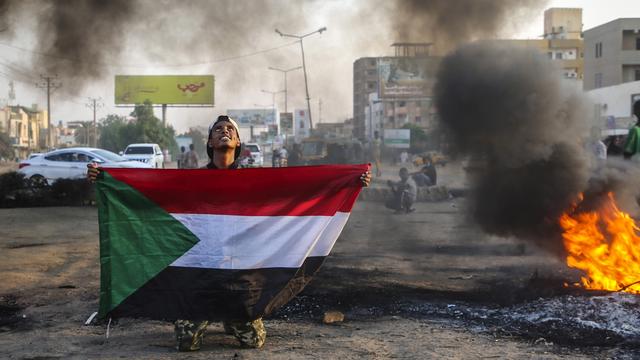 Un manifestant brandit le drapeau national sur le lieu d'affrontements à Karthoum, 26.10.2021. [EPA/Keystone - Mohammed Abu Obaid]