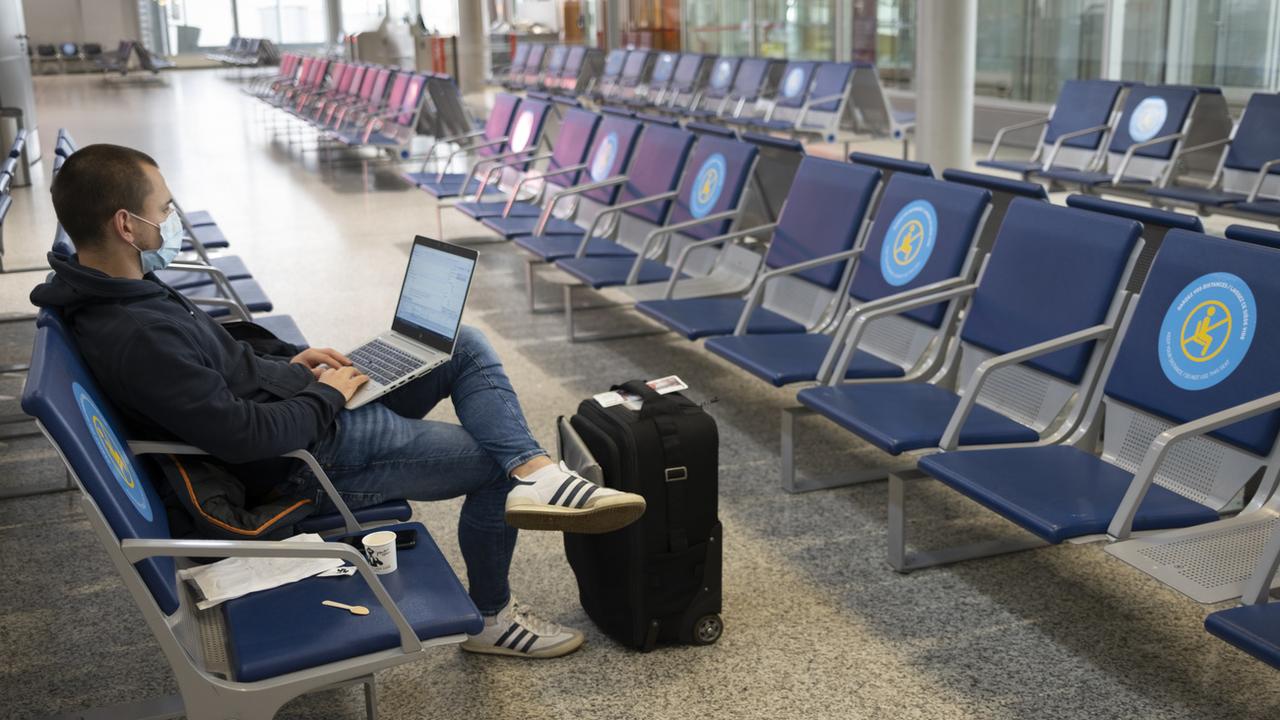 Un homme attend dans une salle d'embarquement de l'aéroport de Genève, le 10 novembre 2020. [Keystone - Laurent Gillieron]