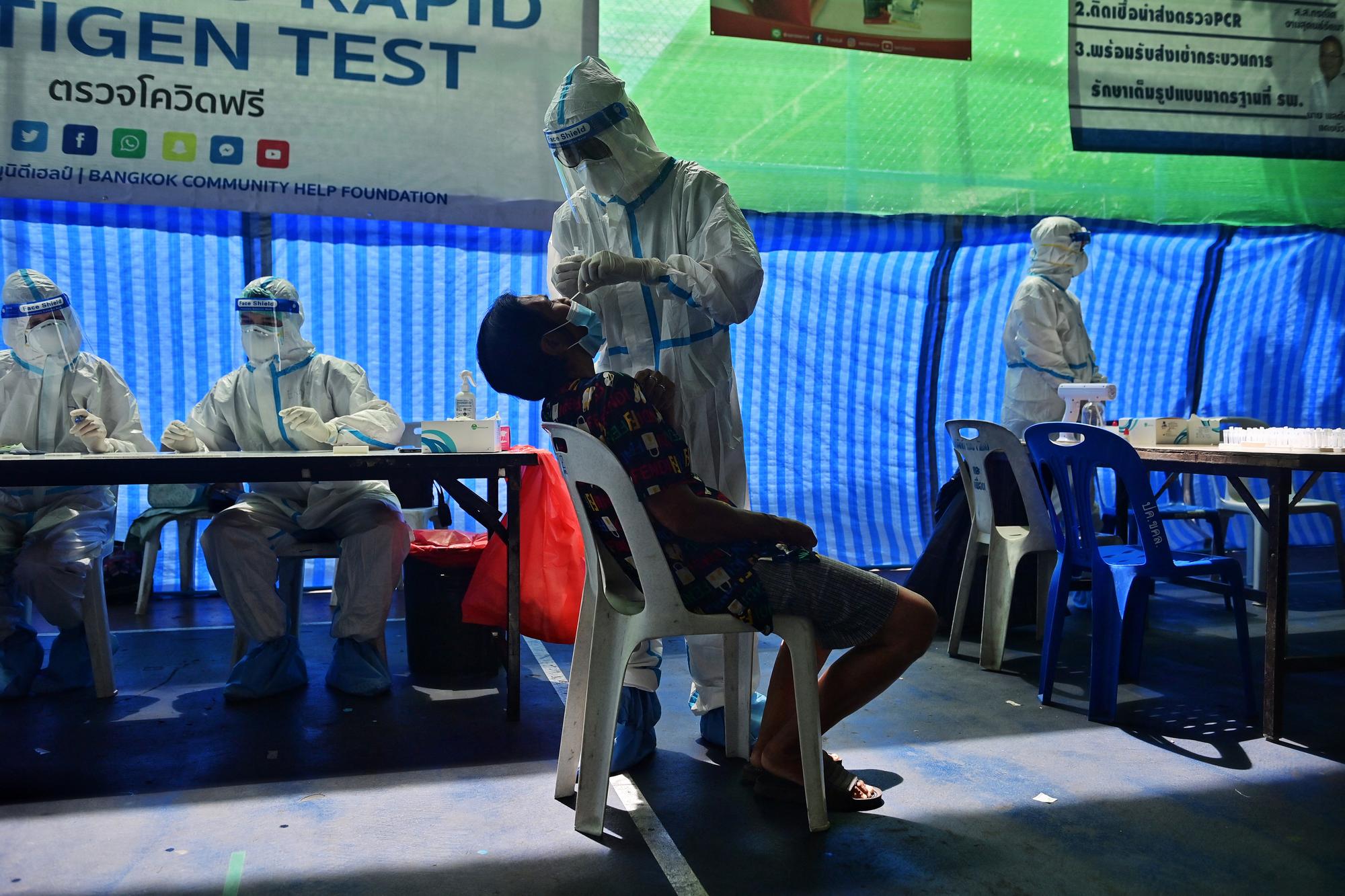 Un membre de l'organisation Bangkok Community Help Foundation procède à un test antigénique rapide sur un résident de Khlong Toei. [AFP - Lillian Suwanrumpha]