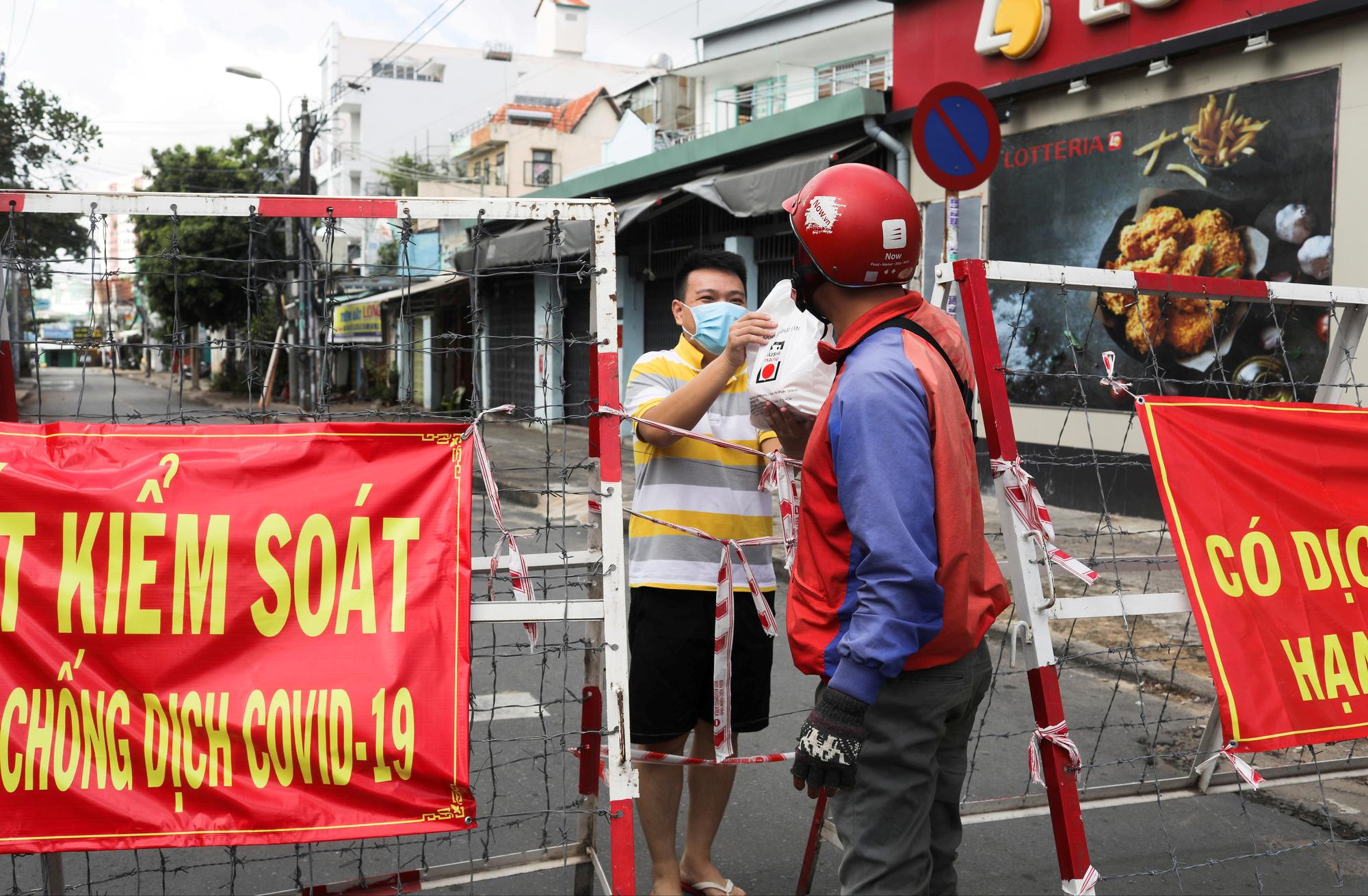 Un homme se fait livrer de la nourriture car son quartier à Ho Chi Minh-ville est barricadé, le 20 juillet 2021. [Reuters - Stringer]