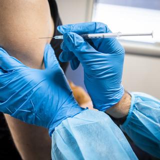 Une personne de l'équipe de vaccination administre avec une seringue une dose de vaccin contre le Covid dans une unité mobile de vaccination sur la place de la Riponne lors de la Semaine nationale de la vaccination le mardi 9 novembre 2021 à Lausanne. [Keystone - Jean-Christophe Bott]