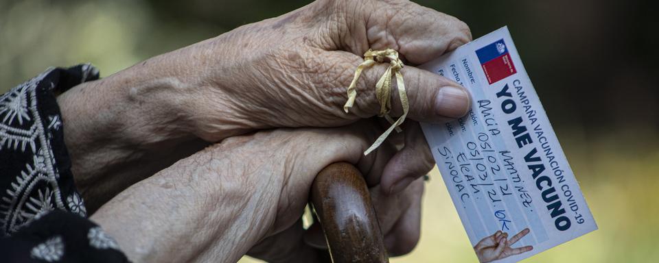 Alicia Martinez tient sa carte de vaccination: elle vient de recevoir la seconde injection du sérum de Sinovac. Santiago, Chili, le 5 mars 2021. [Keystone/AP Photo - Esteban Felix]