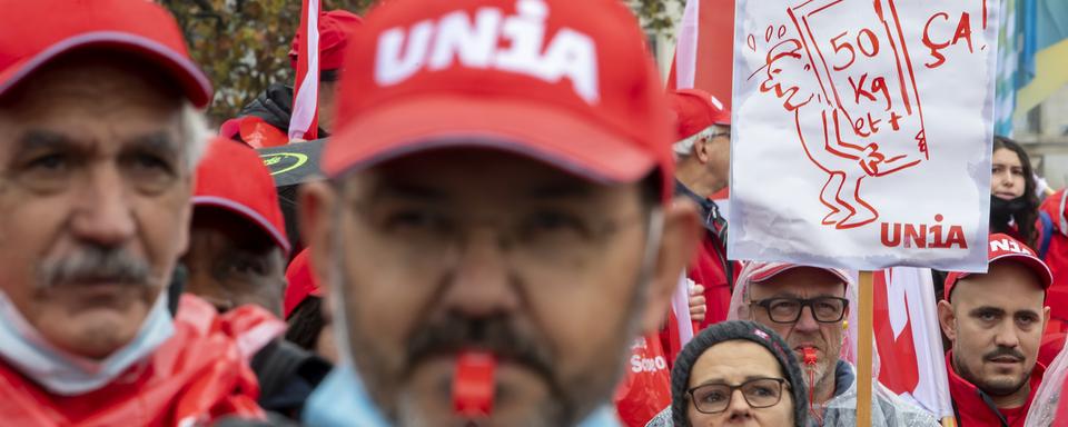 Des personnes participent à une manifestation syndicale pour une revalorisation des salaires et des conditions de travail dans la construction et d'autres domaines, le 30 octobre 2021 à Genève. [Keystone - Martial Trezzini]