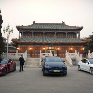 Des voitures Tesla devant un bâtiment à Pékin. [Keystone/AP Photo - Mark Schiefelbein]
