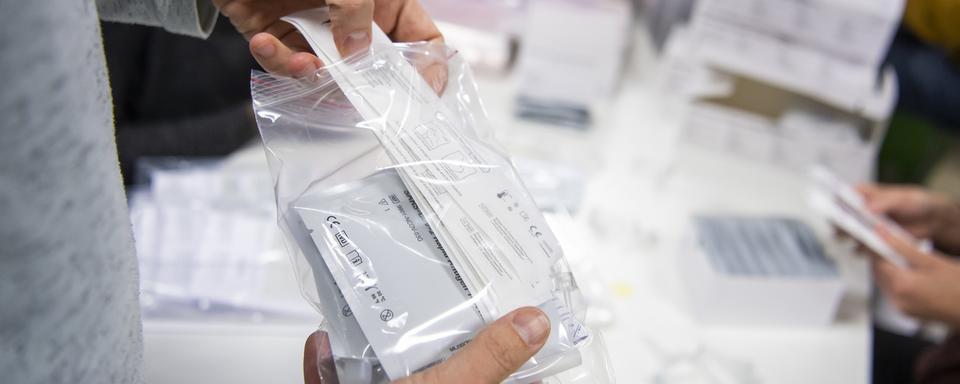 Un sachet contenant des autotests pour le dépistage du coronavirus. [Keystone - Jean-Christophe Bott]